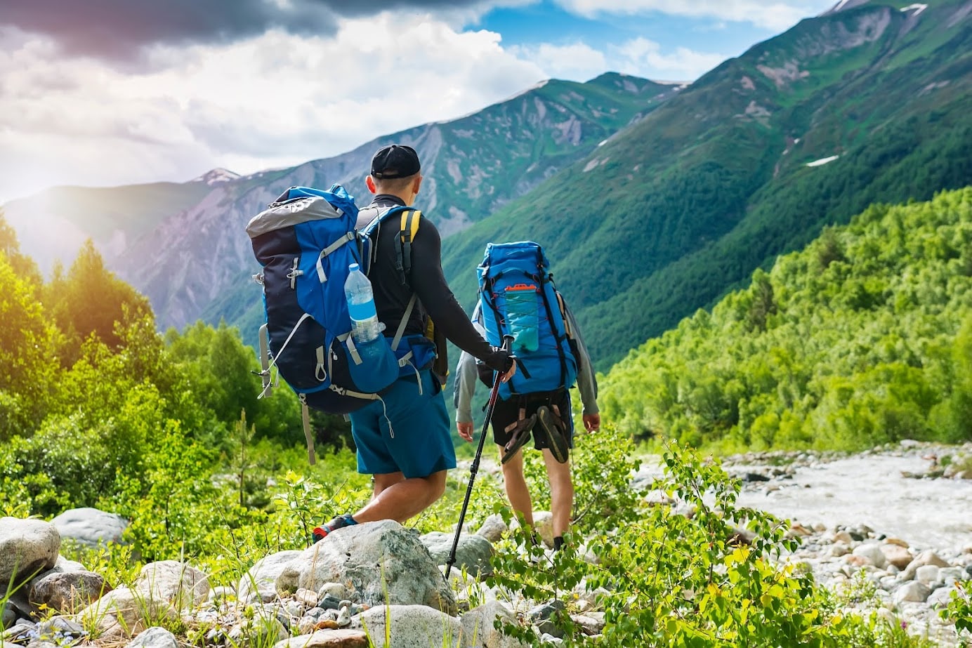 Trekking in mountains. Mountain hiking. Tourists with backpacks hike on rocky way near river. Wild nature with beautiful views. Sport tourism in Svaneti, Georgia. Hikers and climbers in mounts; Shutterstock ID 1183637155